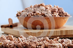 Brown chocolate flawored popcorn on the wood plate with cinnamon