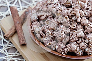 Brown chocolate flawored popcorn on the wood plate with cinnamon