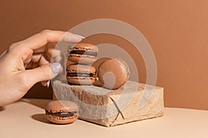 Brown chocolate macaroons with paper box on beige background. Sweet food. Tasty desert. Homemade meal. Delicious food. Space for