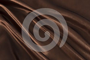 Brown or chocolate silk satin fabric texture background.Cloth soft wave.
