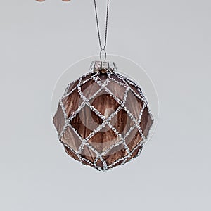 Brown Christmas ball with concave patterns ornamented with a shiny mesh