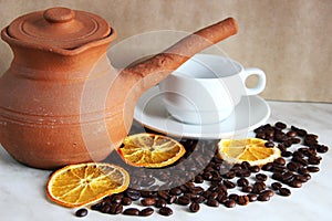 brown clay dishes, white clean Cup and saucer, roasted coffee beans and dried orange