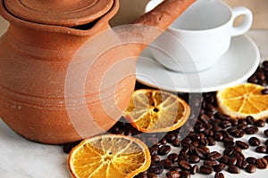 brown clay dishes, white clean Cup and saucer, roasted coffee beans and dried orange