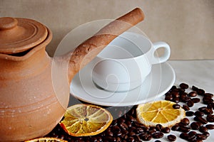 brown clay dishes, white clean Cup and saucer, roasted coffee beans and dried orange on the table