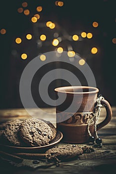 Brown clay vintage coffee mugs and delicious chocolate chip cookies on a wooden table in warm colors