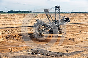 Brown coal open pit landscape with digging excavator in Germany