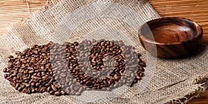 Brown coffee beans on the bag with empty wooden dish