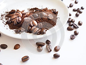 Brown coffee beans and ground coffee on a white cup