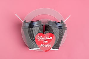 Brown coffee cups, red heart-shaped sticker on pink background.