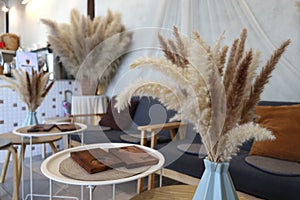 Brown color of dried grass flower in the vase decoration with neutral color sofa seating
