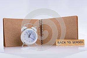 Brown color notebook and alarm clock