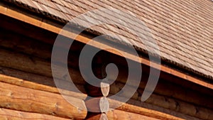 Brown colored log house wall with tar oiled cedar wooden shingle roof