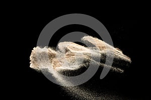 Brown colored sand splash.Dry river sand explosion isolated on black background. Abstract sand cloud