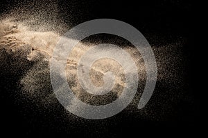 Brown colored sand splash.Dry river sand explosion isolated on black background. Abstract sand cloud