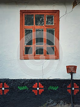 Brown colored wooden window framed into a cracked wall painted with light blue lime. Closeup architectural details of an old,