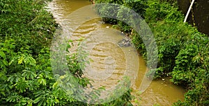 Brown coloured dirty river in Bogor indonesia photo