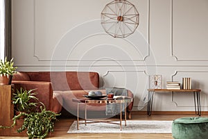 Brown comfortable corner sofa in elegant living room interior with grey wall with molding and fancy clock