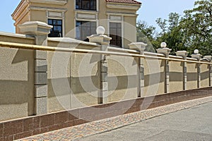 Brown concrete fence in front of a house in the street near an asphalt road