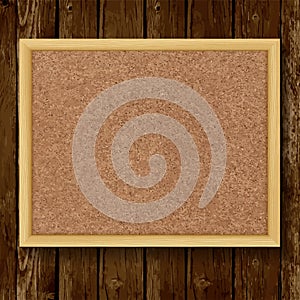 Brown cork board in a frame on wood background.