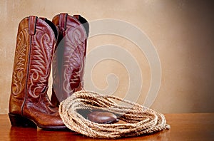 Brown cowboy boots and a coil of rope on brown