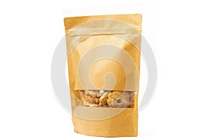 Brown craft food packaging in paper, plain doypack standup bag filled with biscuits with window and zipper on white background