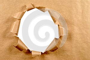 Brown craft paper background with untidy torn hole, white copy space