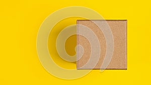 Brown craft paper or carton box with lid mock up on yellow background. Top view of blank small paper box. Brown cardboard box.