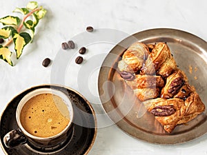 A brown cup with espresso next to maple pecans with nuts and syrup. Fresh coffee beans, ivy branch. Located on a gray background.