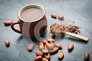 Brown cup of fresh cocoa drink with cocoa beans and powder