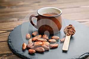 Brown cup of fresh cocoa drink with cocoa beans and powder