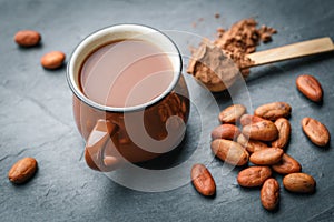 Brown cup of fresh cocoa drink with cocoa beans and powder