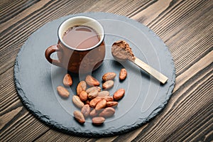 Brown cup of fresh cocoa drink with cocoa beans and powder