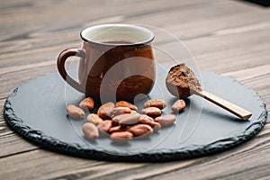 Brown cup of fresh cocoa drink with cocoa beans and powder