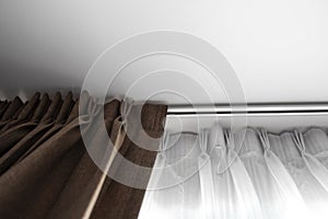 Brown curtains and white tulle on a rail with a white ceiling. Curtain interior decoration in living or sleeping room