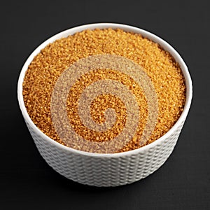 Brown Demerara Sugar in a Bowl on a black background, low angle view