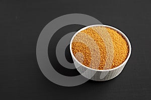 Brown Demerara Sugar in a Bowl on a black surface, low angle view. Copy space