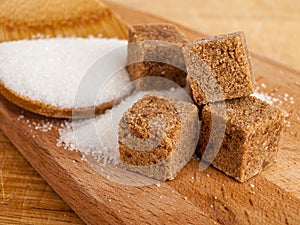 Brown diced cane sugar, refined sugar, white sugar on a wooden plate, sugar consumption concept, easily digestible