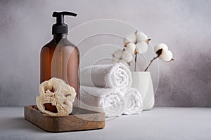 Brown dispenser bottle, loofah sponge and white towels