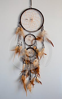 Brown dream catcher with orange plumage on a white background and copy space