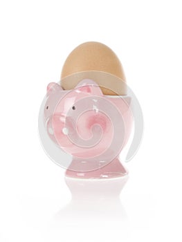 Brown egg in easter pink pig cup isolated on white