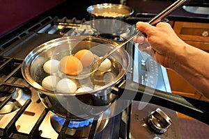 Brown eggs being removed from boiling water on gas stove photo