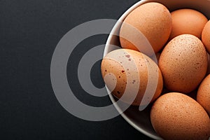 Brown eggs in bowl isolated on dark background