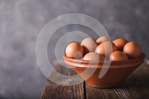 Brown eggs in a brown ceramic bowl on wooden table on an gray abstract bbackground. Rustic Style. Eggs. Easter photo concept