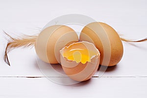 Brown eggs in carton box. Eggshell with egg yolk inside on white wooden background. copy space