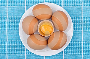 Brown eggs in glass plate on blue tablecloth