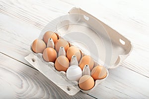 brown eggs and among them one white egg in carton box. Concept of difference, dissimilarity, stranger. space for text