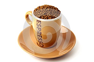 Brown elegant cup full of instant coffee granules, saucer under it. View from above, so it makes perfect round shape.