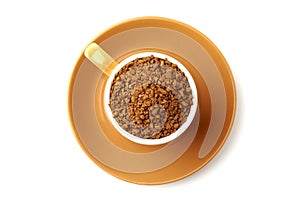 Brown elegant cup full of instant coffee granules, saucer under it. View from above, so it makes perfect round shape.