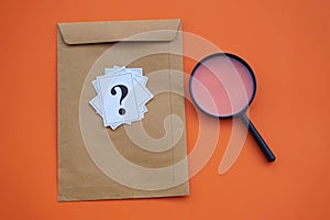 Brown envelope,magnifying glass and paper cards of question marks