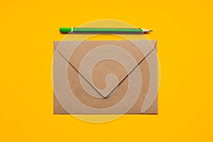 Brown envelope and simple green pencil on a yellow background